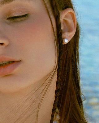 Aretes Amatista con perla blanca dorados puestos en oreja, joya Pialü