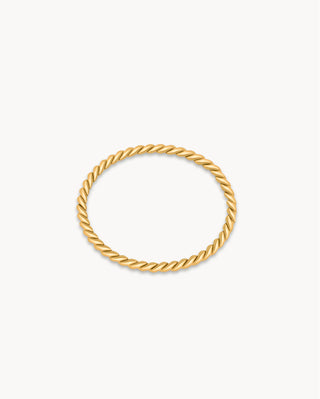 Anillo fino dorado con textura trenzada delicada sobre fondo blanco, joya waterproof de Pialü