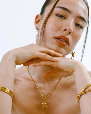 Aretes dorados estrella y luna puestos en modelo, waterproof de Pialü
