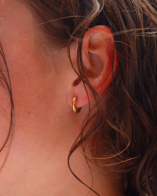Argollas doradas pequeñas Bisou en oreja de modelo, joya waterproof de Pialü