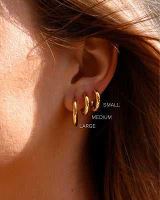 Aros dorados lisos sobre fondo blanco, ángulo frontal, joya waterproof de Pialü
