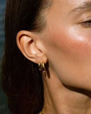 Aros dorados Gala usados en oreja de modelo en conjunto de tres pares, joya waterproof de Pialü