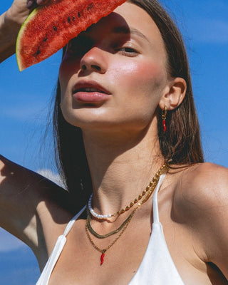 Detalle de collar con dije de ají rojo y cadena dorada en cuello, waterproof de Pialü