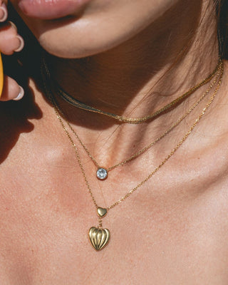 Modelo con collar dorado corazón estriado Mykonos, acero inoxidable waterproof de Pialü