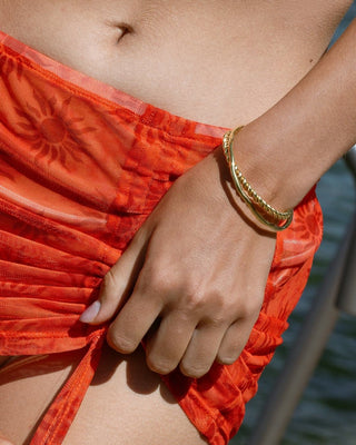 Modelo luciendo brazalete rígido dorado trenzado en muñeca, joya waterproof de Pialü