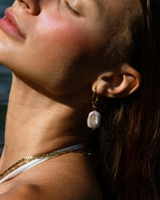 Argollas doradas ovaladas con perla barroca natural larga en modelo waterproof de Pialü
