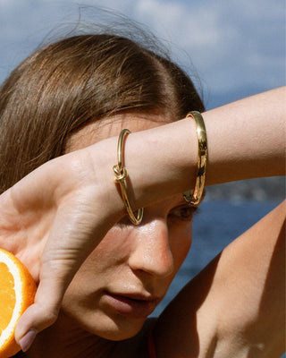 Modelo con pulsera dorada tipo bangle con nudo central, joya waterproof de Pialü