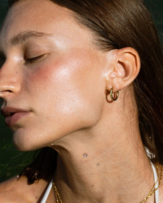 Argollas dobles doradas con zircones puestas en oreja de modelo, joya waterproof de Pialü