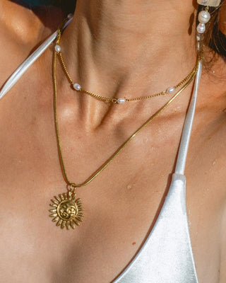 Modelo usando collar dorado con perlas barrocas naturales sobre escote, waterproof de Pialü