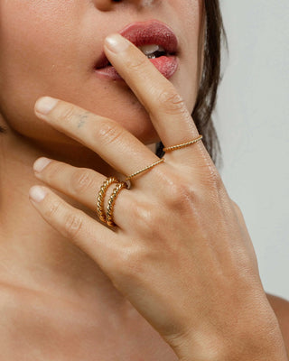 Par de anillos trenzados en dorado sobre fondo claro, acero inoxidable waterproof de Pialü