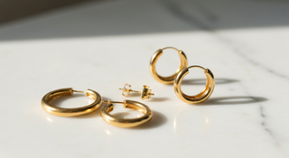 Aretes dorados elegantes sobre marmol blanco - guia de aretes segun tipo de rostro