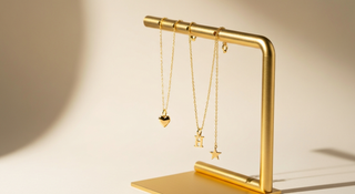 Collares con dijes personalizados colgando de soporte dorado