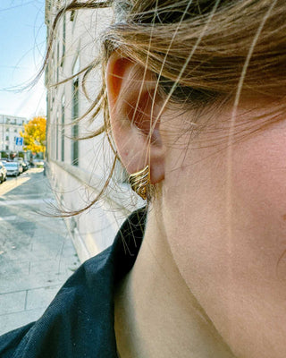 Aretes dorados tipo llama puestos en modelo, aretes waterproof de Pialü