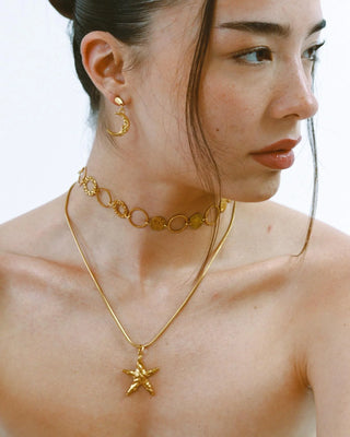 Detalle de aretes asimétricos dorados estrella y luna, waterproof de Pialü