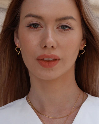 Aretes esfera dorada en oreja de modelo, joya waterproof de Pialü