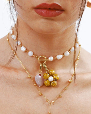 Collar charm corazón cuarzo rosa ángulo lateral, cadena dorada con múltiples colgantes Pialü