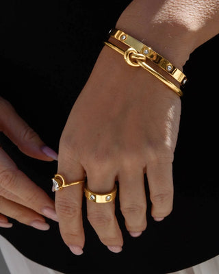 Brazalete rígido dorado con incrustaciones brillantes sobre fondo neutro, waterproof de Pialü