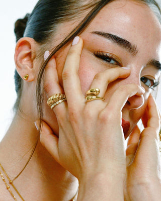 Modelo con aretes stud corazón dorado puestos, joya resistente al agua de Pialü