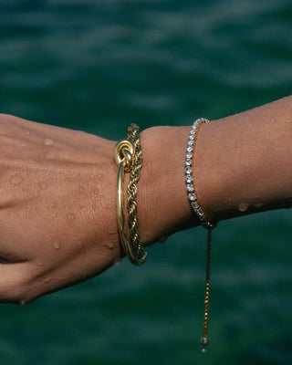 Pulsera tennis dorada zircones blancos sobre superficie blanca, joya waterproof de Pialü